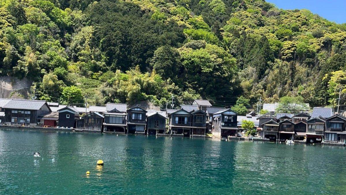 伊根の舟屋。海沿いに並ぶ木造の家と緑の山